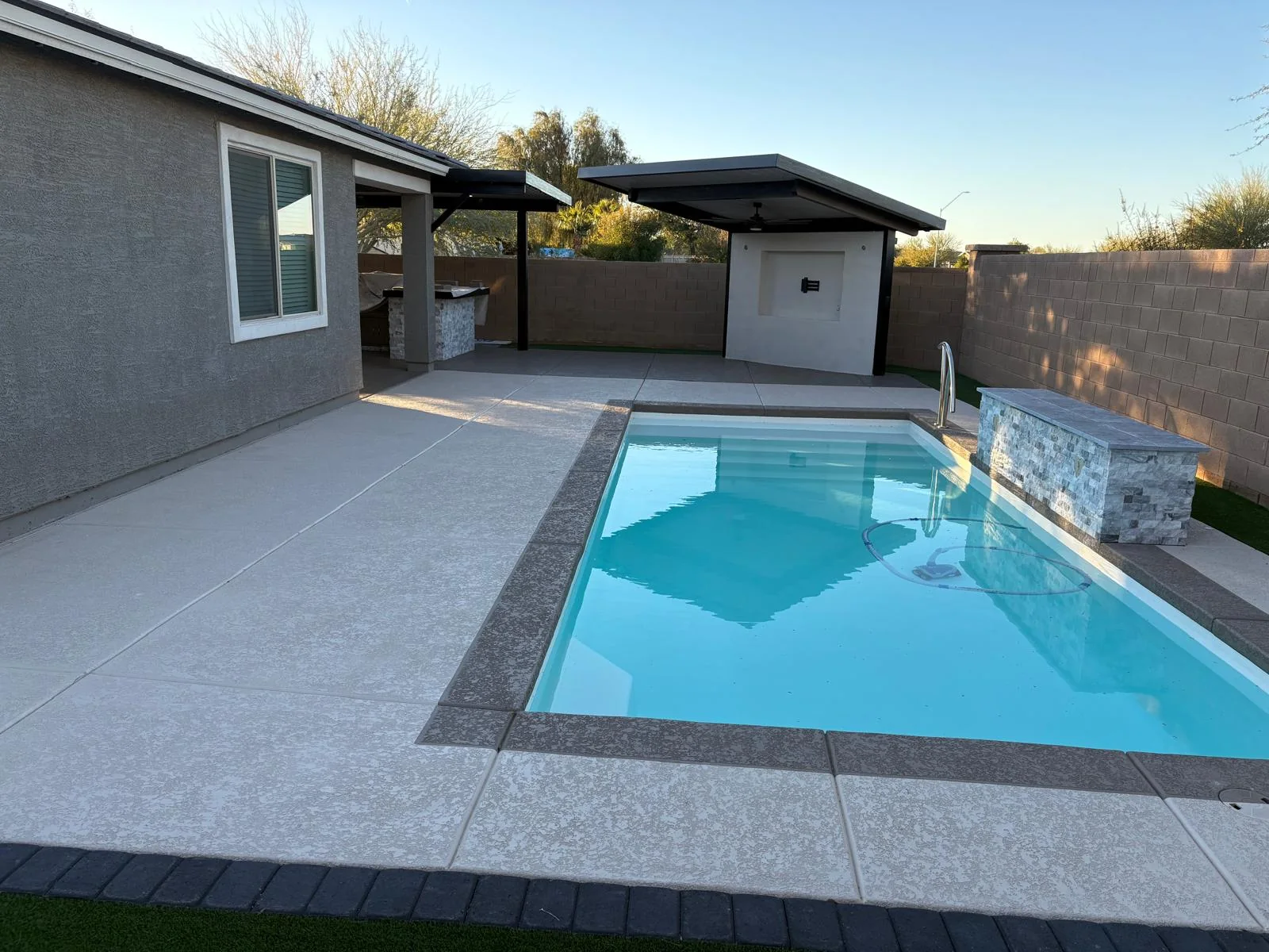 Finished textured concrete pool deck around a compact residential pool